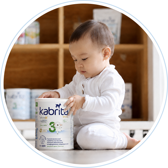 Ребенок осматривает банку смеси Kabrita 2 gold
